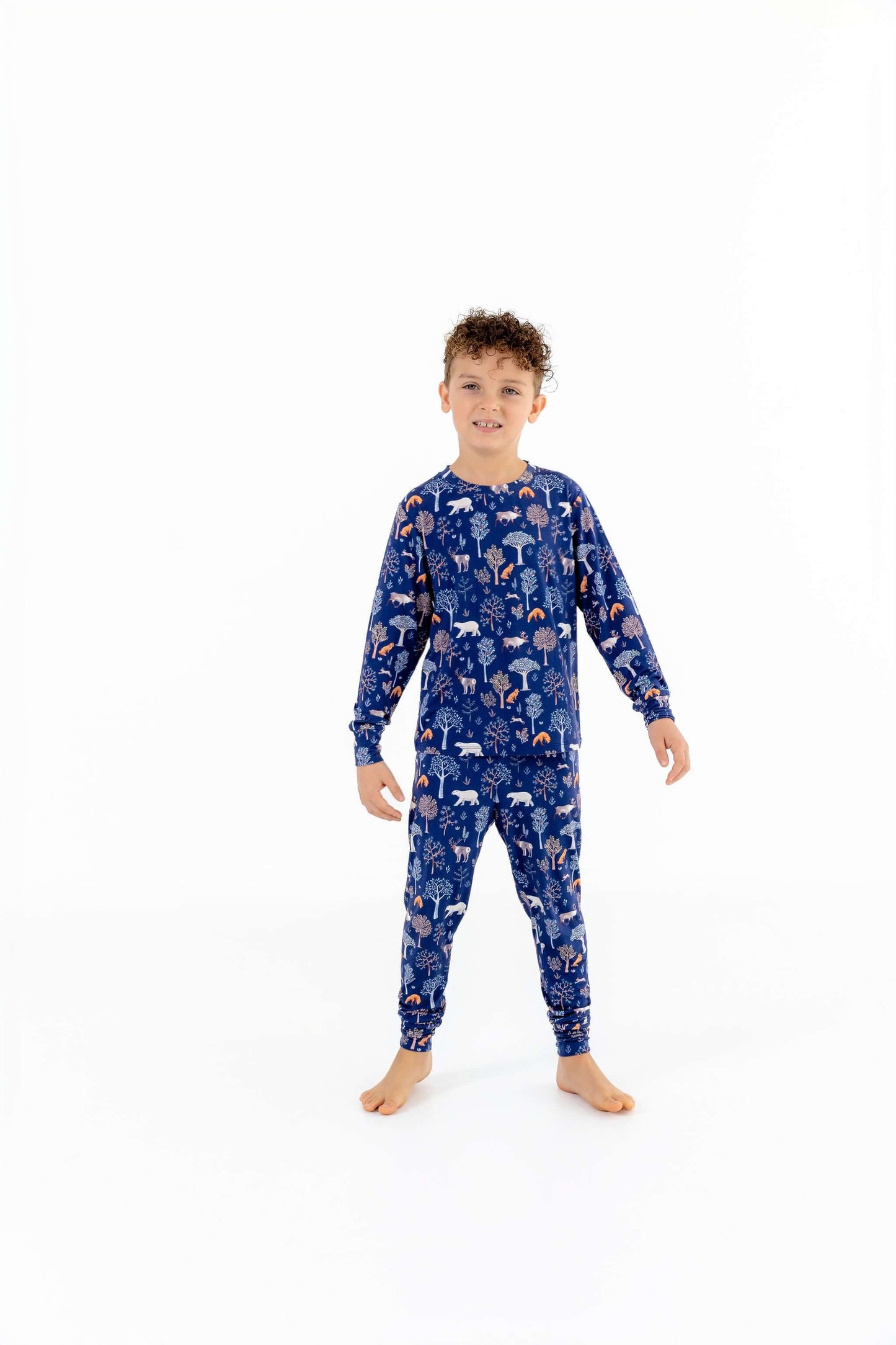 Front view of child wearing kids pajama set in Woodland Night forest print