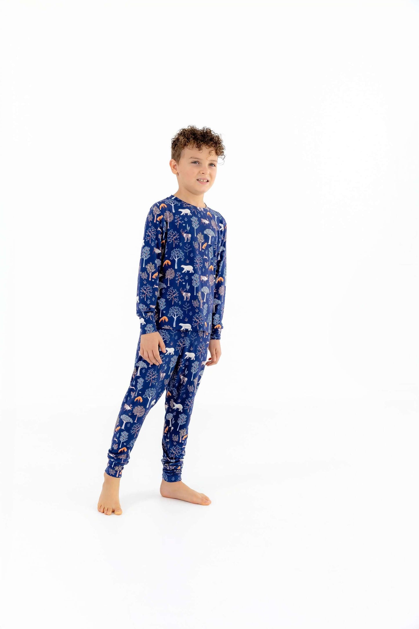 Front view of child wearing kids pajama set in Woodland Night forest print