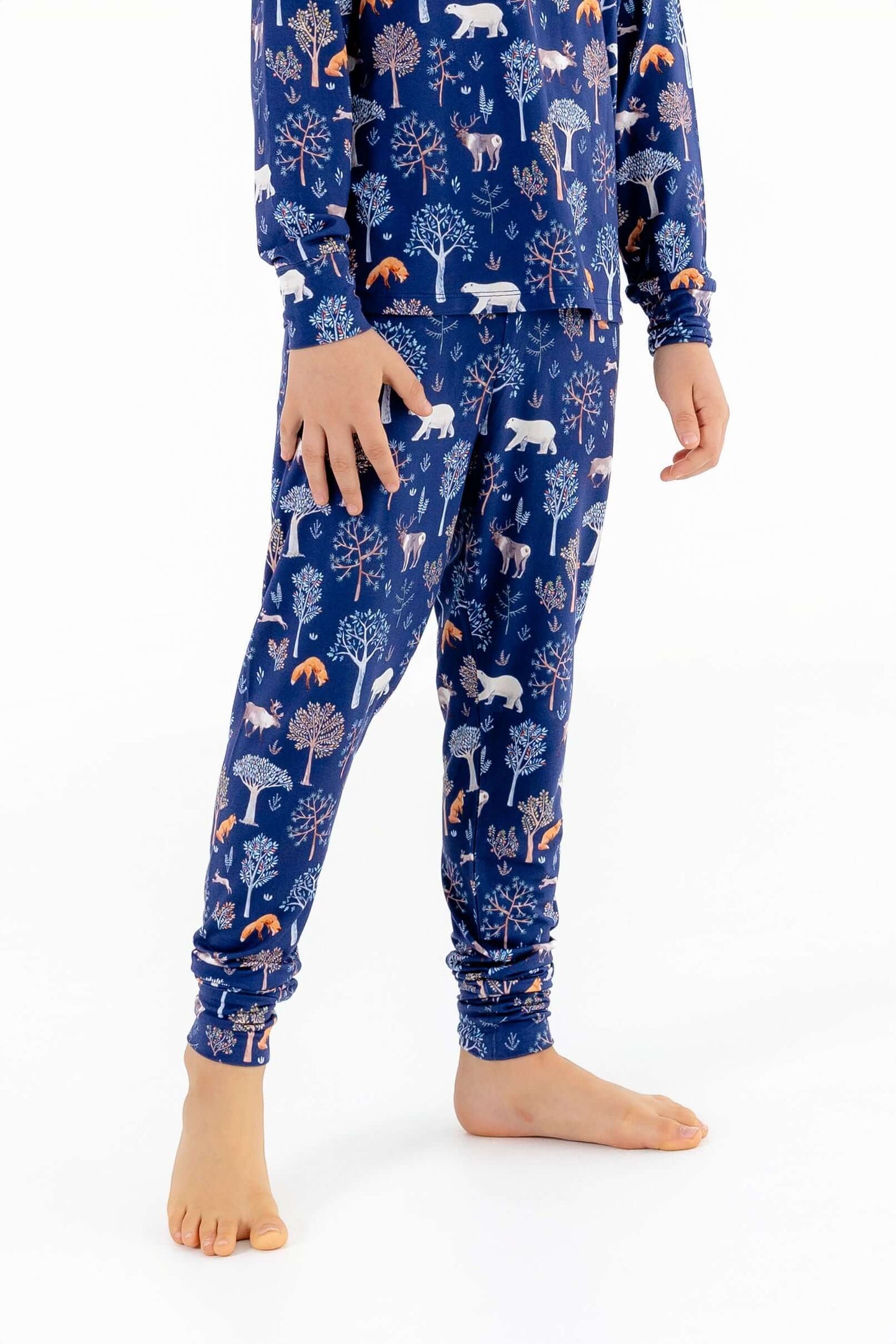 Front view of child wearing kids pajama set in Woodland Night forest print