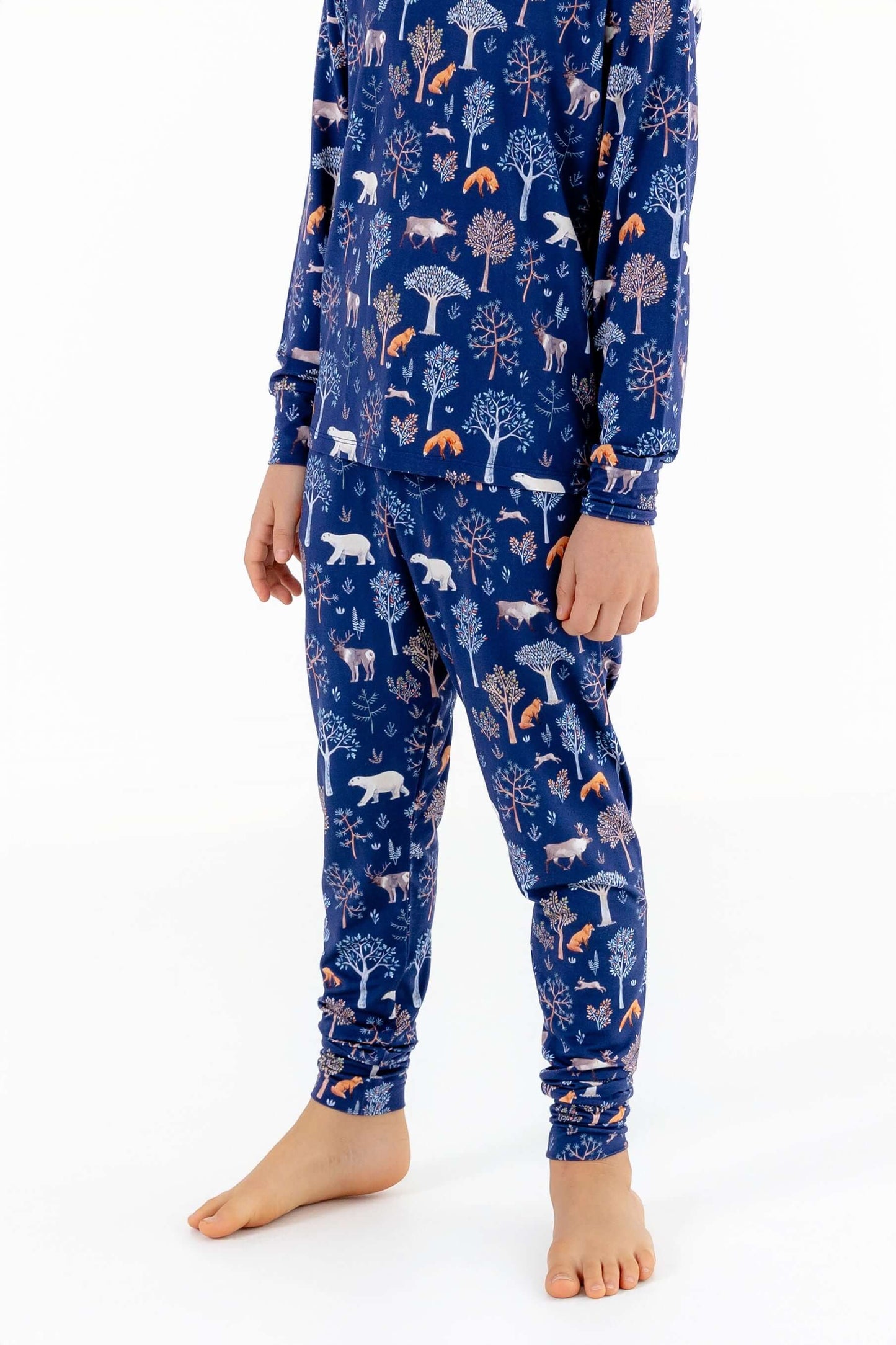 Front view of child wearing kids pajama set in Woodland Night forest print