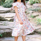 Young girl in a floral dress standing on stone steps in a garden