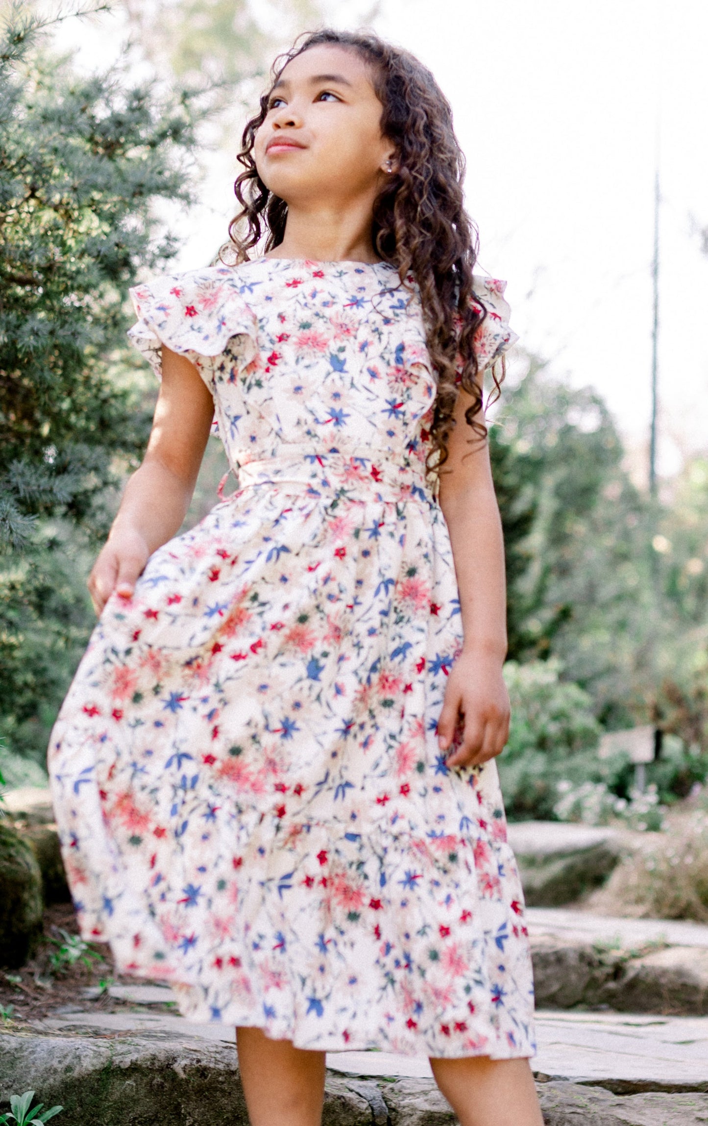Woman in a floral dress standing on stone steps in a garden