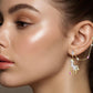 Close-up of a woman wearing a unicorn-themed earring against a neutral background